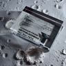 Close-up piece of SR-71 Blackbird titanium embedded in clear acrylic. The fragment is metallic and jagged, which highlights its history from the high-speed reconnaissance aircraft. A blueprint of the SR-71 aircraft is visible in the display.