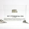 Close-up piece of SR-71 Blackbird titanium embedded in clear acrylic. The fragment is metallic and jagged, which highlights its history from the high-speed reconnaissance aircraft.